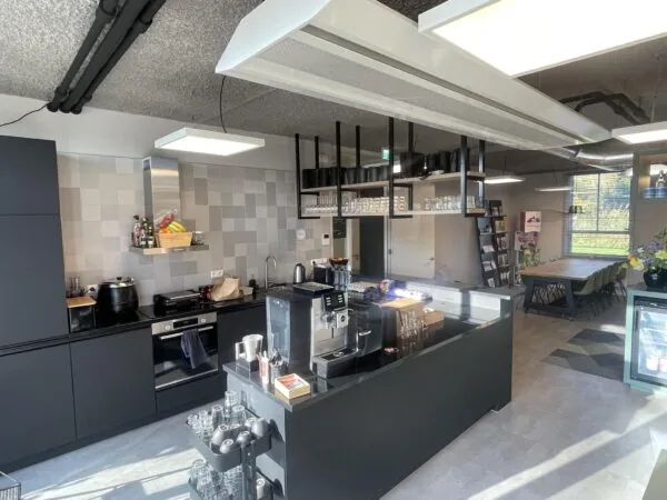 Moderne kantoorkeuken aan de Jan Leentvaarlaan met koffiezetapparaat, glazenrek en aangrenzende vergaderruimte.